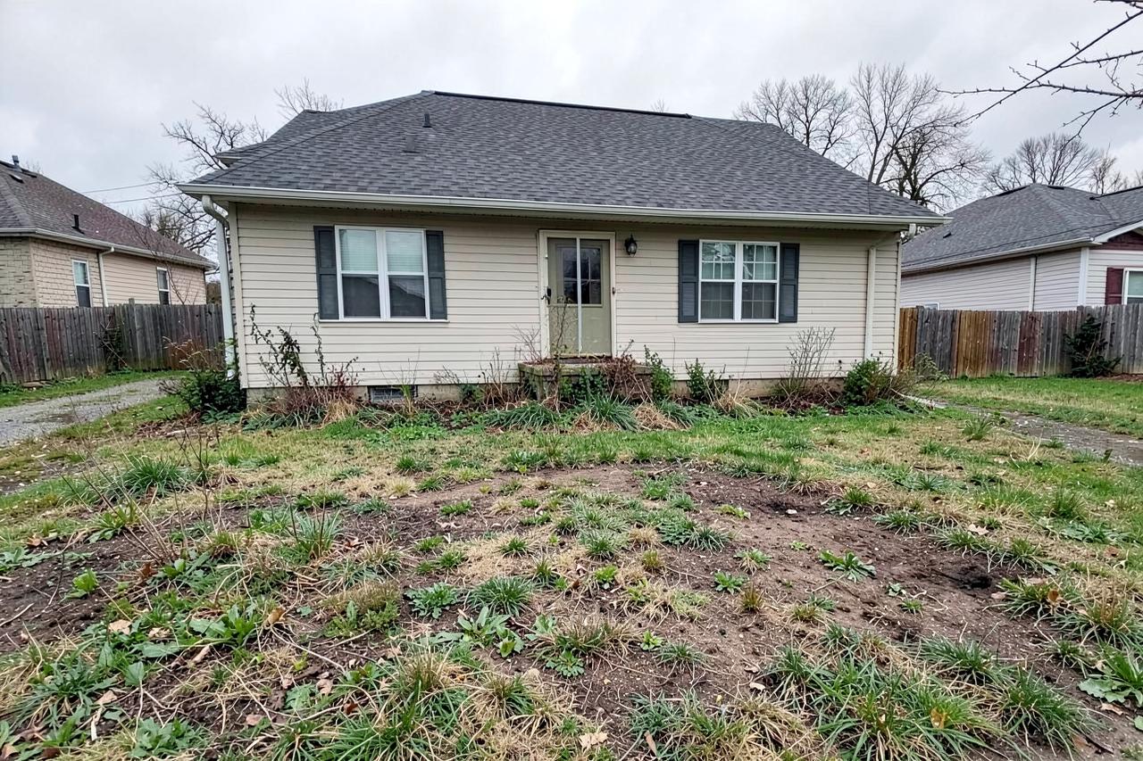 The same front yard before landscaping, with bare dirt and weeds